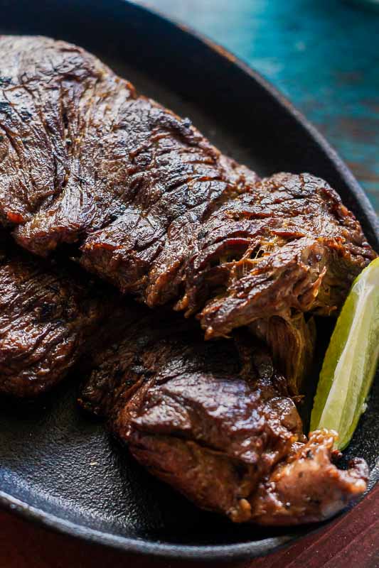 Close up of seared carne asada with a wedge of lime