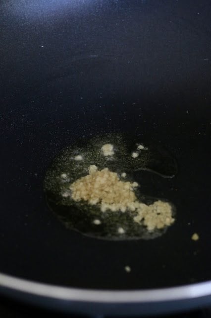 garlic cooking in oil in a wok