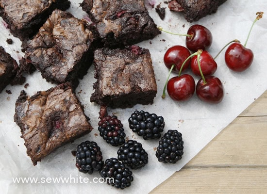 black forest brownies on greaseproof paper with fresh cherries and blackberries.
