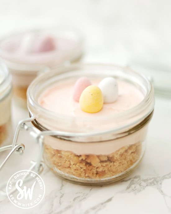 Picnic cheesecakes in little glass jars with mini eggs on top.