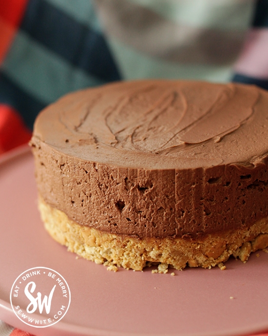 Guinness Chocolate cheesecake ready to be decorated on a pink plate.