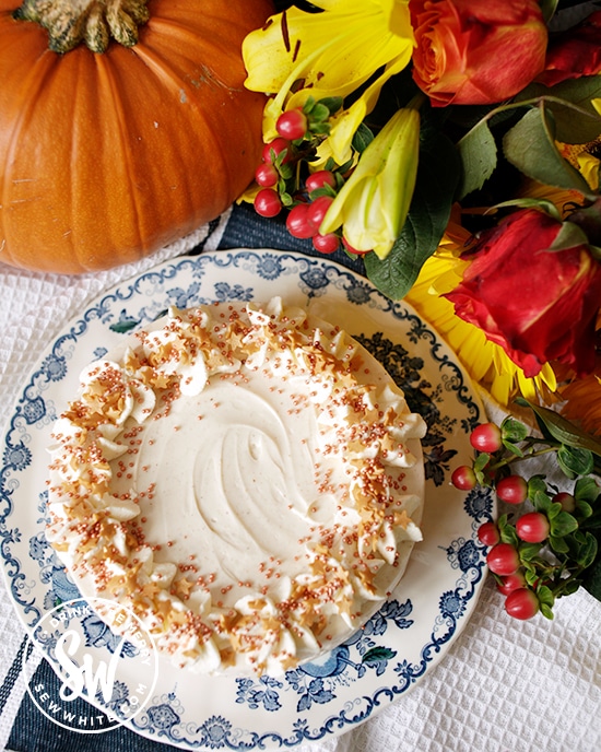 Autumn pumpkin spice cheesecake on a blue plate with a pumpkin and autumn flowers in the background