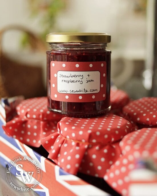 Strawberry and Raspberry Jam in glass jars with red fabric covers.