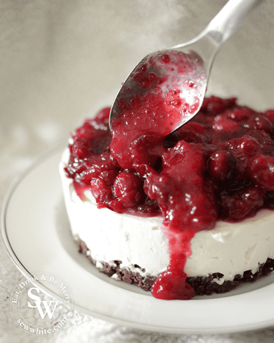 Drizzling the cranberry and orange compote over the cheesecake