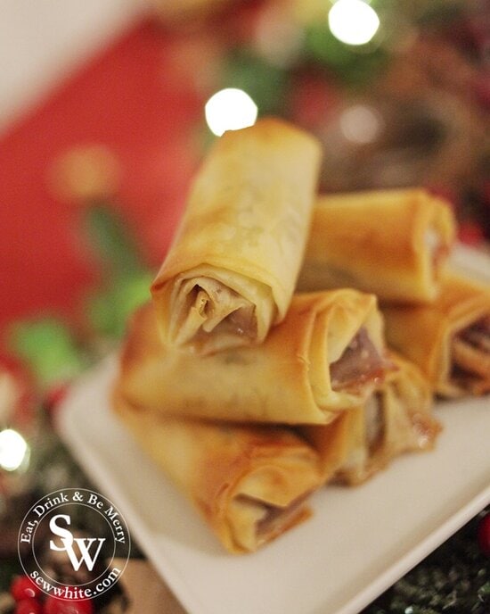 close up of the Mince Pie rolls Christmas finger food waiting to be picked up and eaten. Golden pastry rolls on a white plate