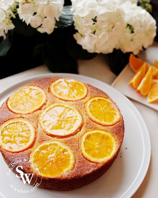 Glistening Orange Drizzle Cake next to white flowers