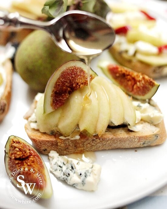 Pears on toast with blue cheese and figs being drizzled with honey.