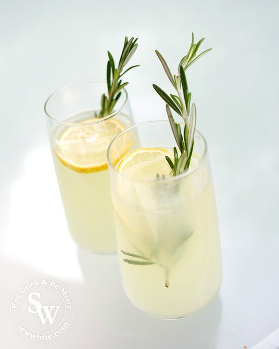 Elderflower and Rosemary Lemonade in tall glasses with large slices of lemon and a bright green sprig of rosemary.