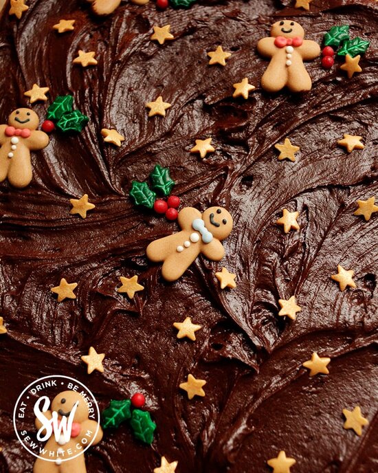 Old School Chocolate Traybake for Christmas with chocolate fudge icing decorated with gingerbread men, gold stars and holly sprinkles