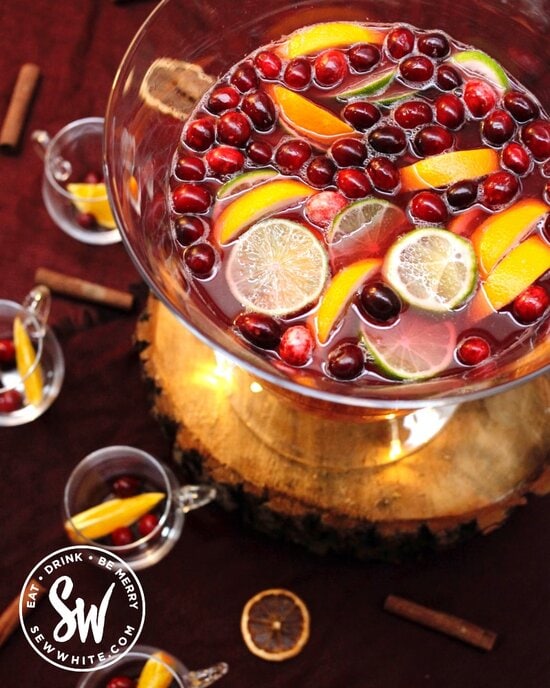 Easy Christmas Cranberry Punch photographed from above in a punch bowl with fresh cranberries and slices of orange and lime in the cocktail