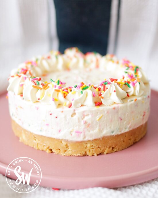 side view of the Funfetti Cheesecake with flecks of sprinkles in the cheesecake batter and decorated on top.