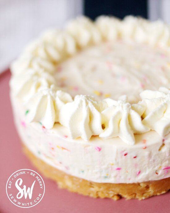 Funfetti Cheesecake with pipped double cream in star shapes on the top before sprinkles have been added.