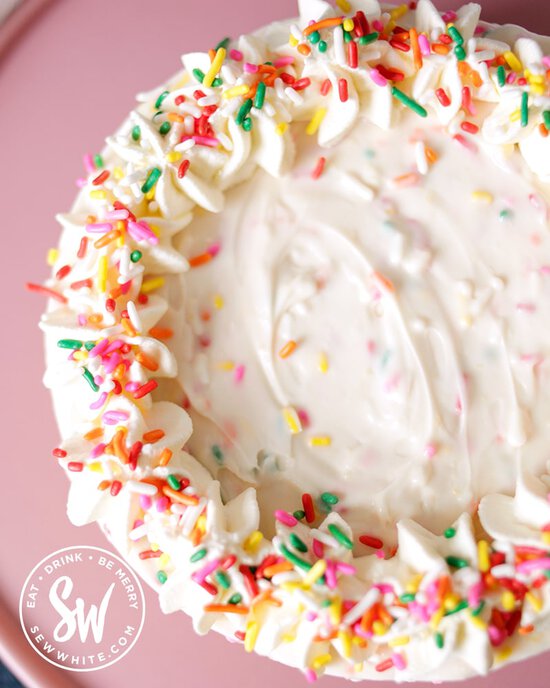 View on top of the sprinkle cheesecake. Sprinkles on top of the pipped cream boarder