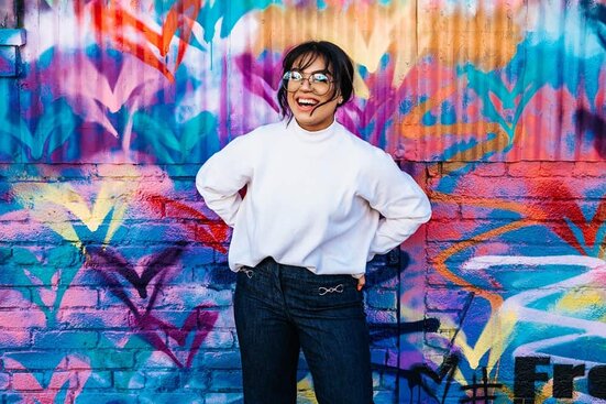 raise your vibration woman smiling with joy in front of heart wall