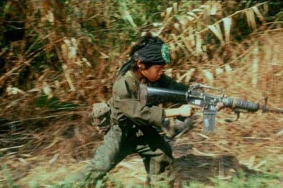 Child soldier holding rifle in the jungle
