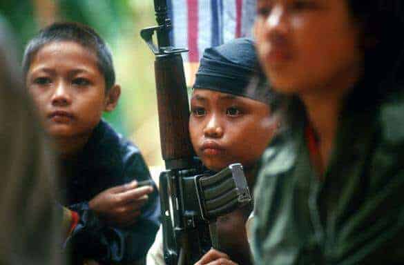 Three young children holding weapons Three young child soldiers holding weapons