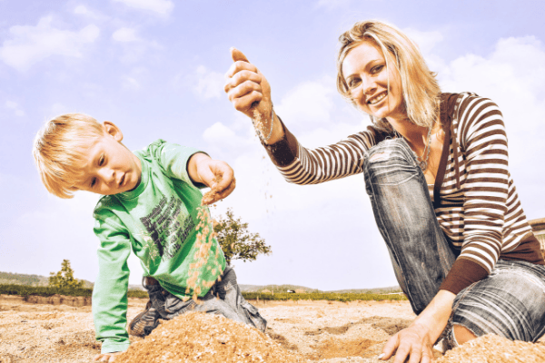 Babysitter mit Kind im Sand