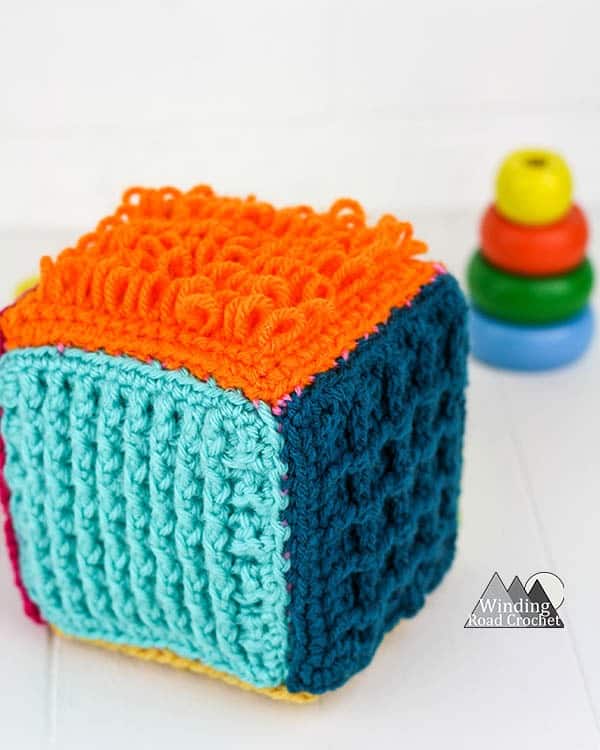 This crochet sensory block is a great toy for babies and toddlers. Learn to make one with this free crochet tutorial. #crochetforbaby #crochetbabytoy