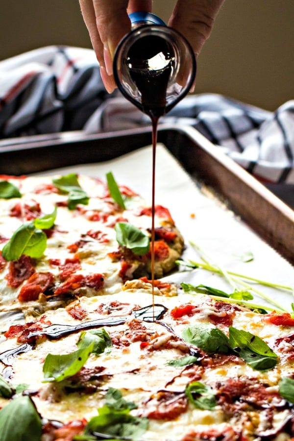Mini Caprese Pizzas with balsamic vinegar being drizzled on top