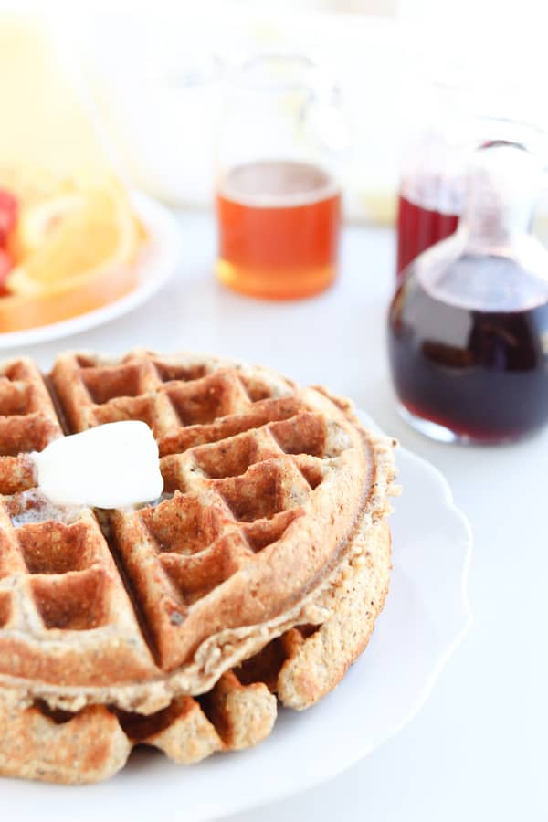 close up of waffles with jugs of honey in the background