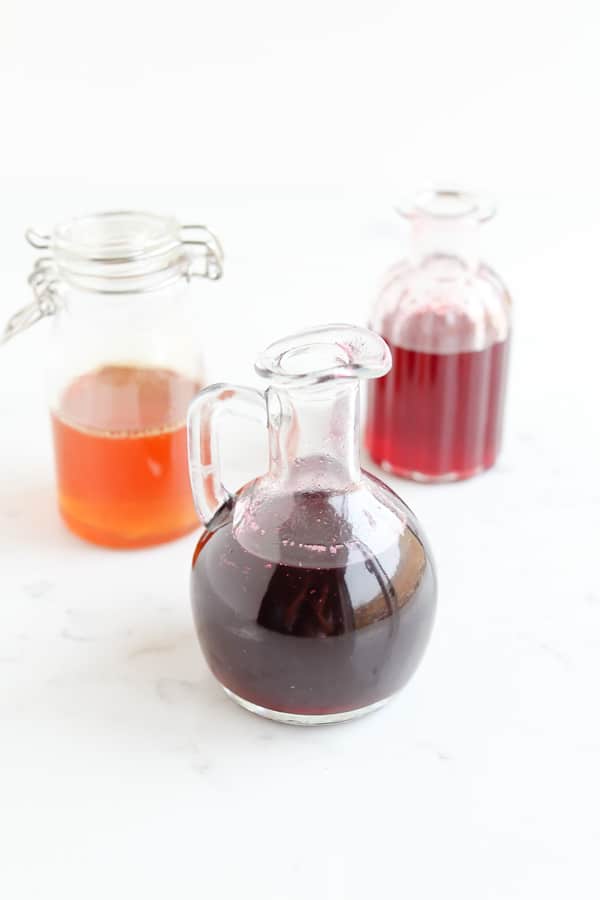 Three jugs of Pressure Cooker Infused Honey Syrup on a marble worktop