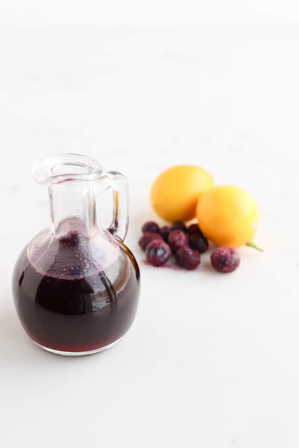 A jar of honey next to blueberries and a lemon