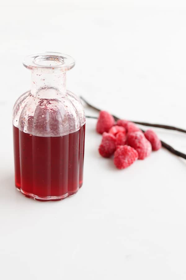A jar of honey next to some raspberries