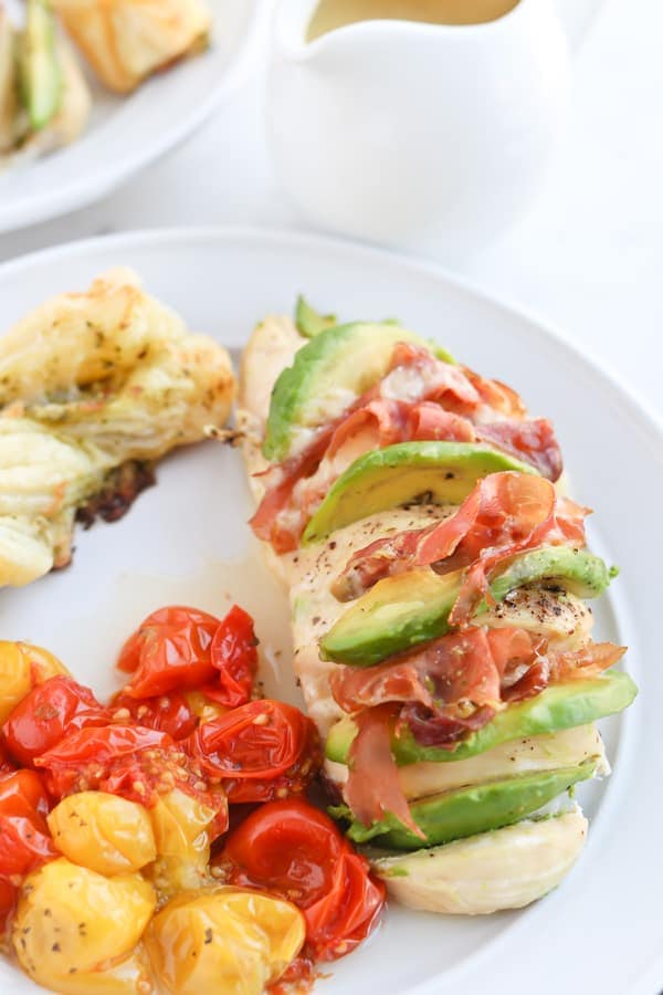 Hassleback chicken on a serving plate with tomatoes
