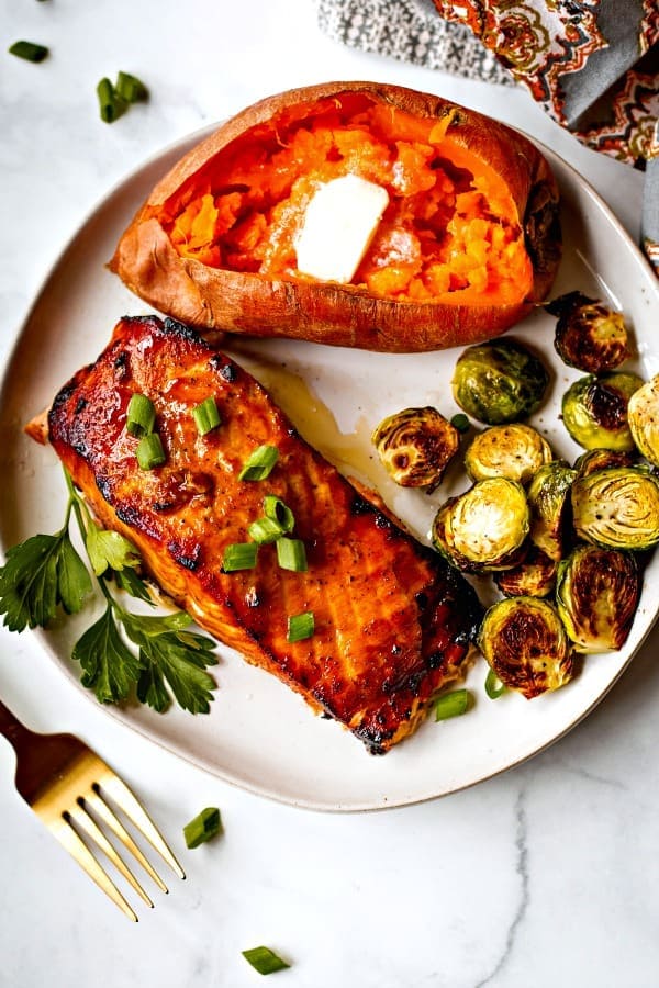 Grilled salmon on a white plate with baked sweet potato