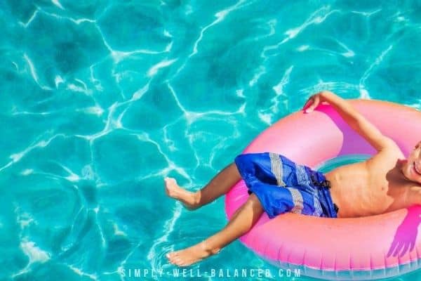 Young boy floating on a blow up toy in pool.