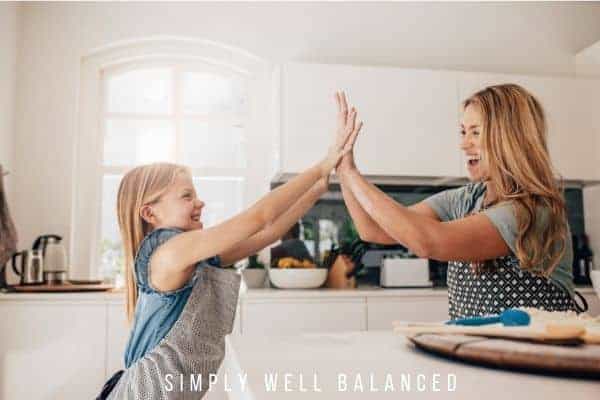 Mom giving daughter a high five in the kitchen