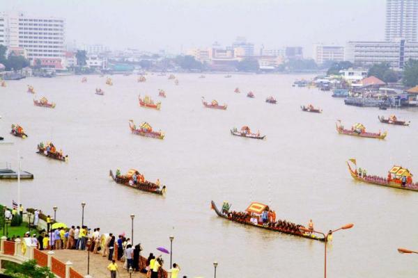 Aerial view of the Royal Barge Processional on the wide Chao Phraya River. The formation stretches to the horizon.