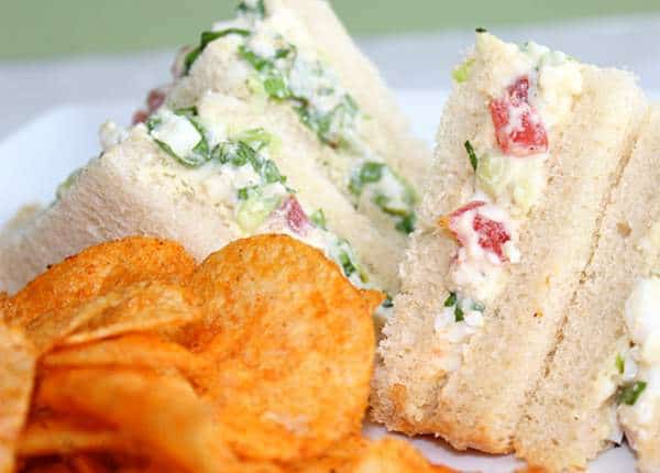 Egg and onion sandwiches on a plate with a side of chips