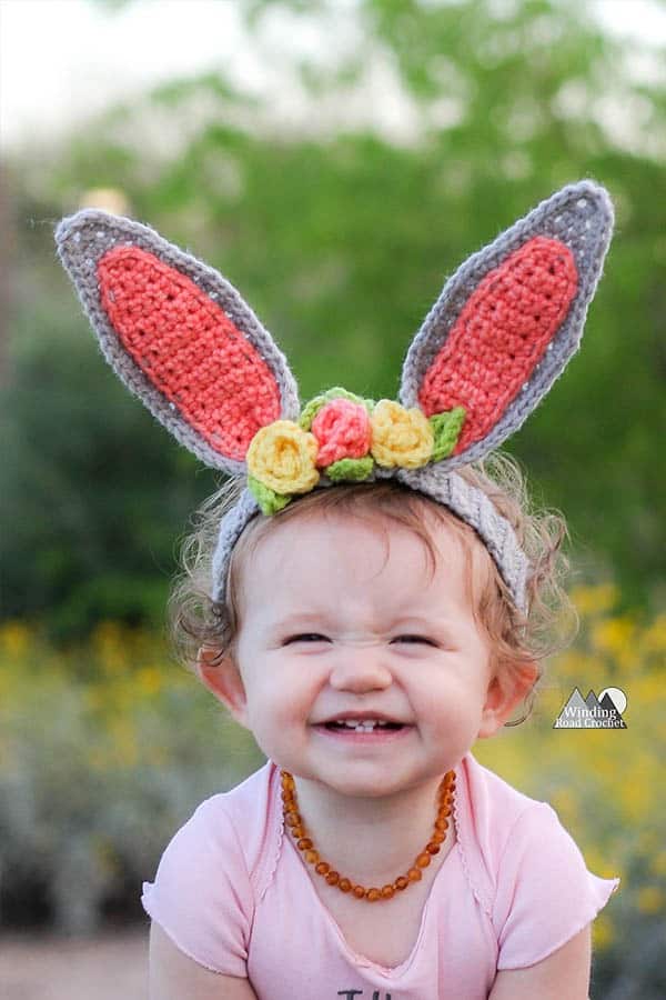 Crochet bunny ear headband with flowers for a child in your life. This is the perfect accessory for easter and spring photos. This free crochet pattern will walk you through the steps to make this baby headband. #crochetheadband #eastercrochet #springcrochet