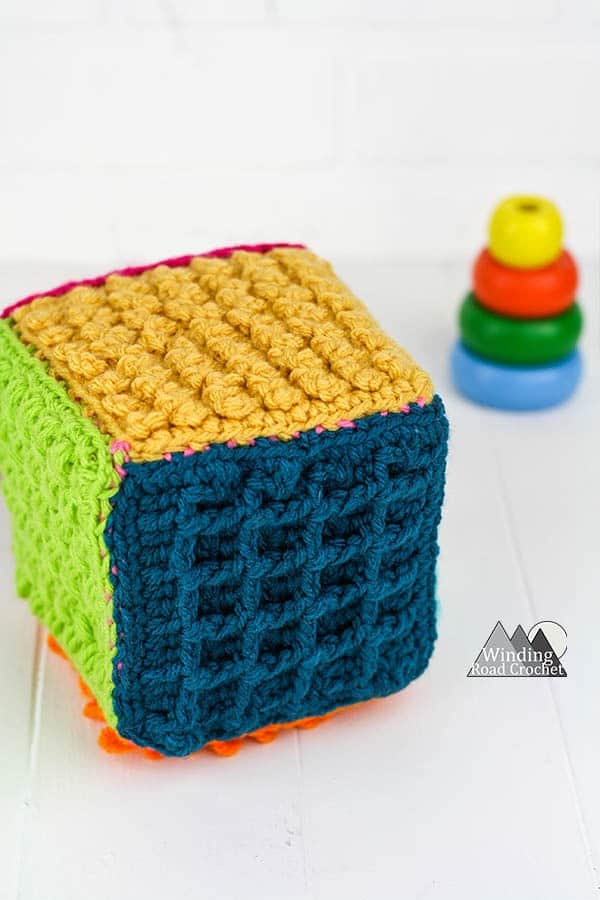 This crochet sensory block is a great toy for babies and toddlers. Learn to make one with this free crochet tutorial. #crochetforbaby #crochetbabytoy