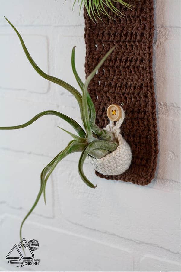 Crochet this quick and easy boho plant hanger. It will add a modern natural element to your home decor. This plant hanger is great to fold air plants, succulents, or small stems of flowers. #airplants #planthanger #crochethomedecor #crochetpattern #free #pattern #crochet #crochetplanthanger #crochetwallhanging