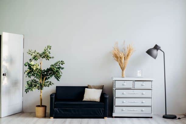 Super small couch and dresser with normal-sized lamp and potted plant