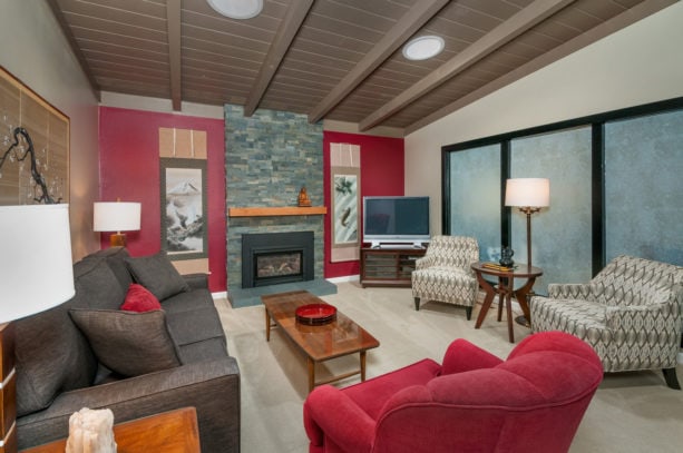 an asian living room with red accent wall and grey fireplace