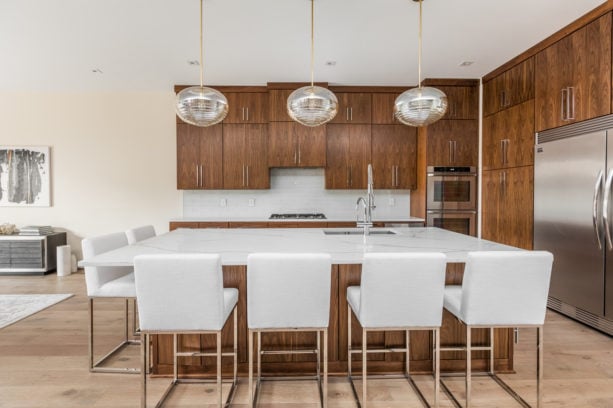 medium tone wood flat panel floor to ceiling cabinets with white backsplash