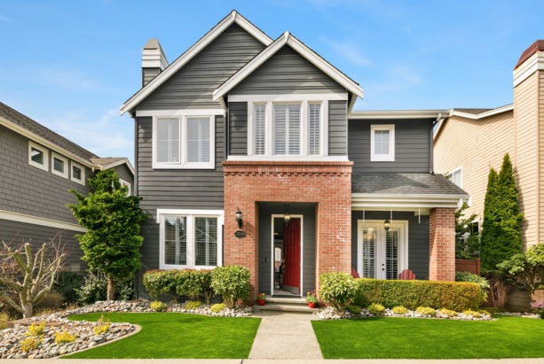 a trendy transitional house with grey siding and red brick combo