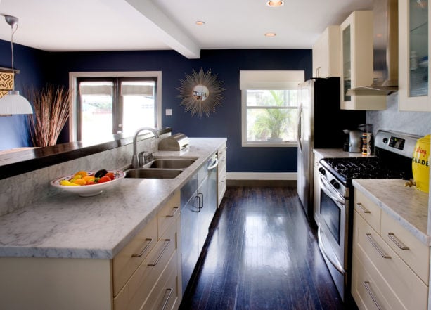 a contemporary kitchen with dark wood floor, white trim, and dark blue walls
