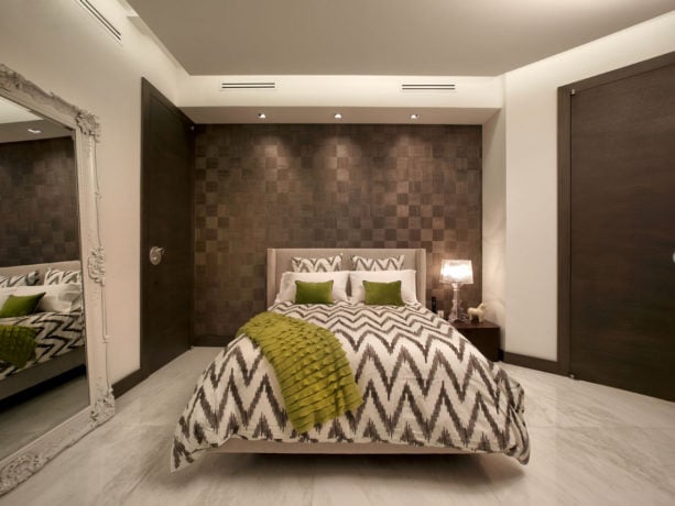 a white and gray bed adorned with decorative pear green throw