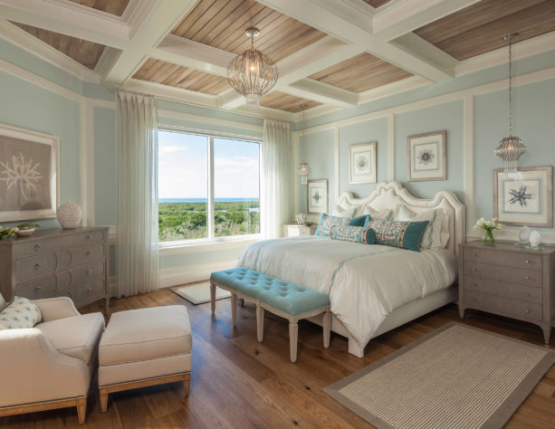 a beach-style bedroom with white trim, soft blue walls, and white oak floor