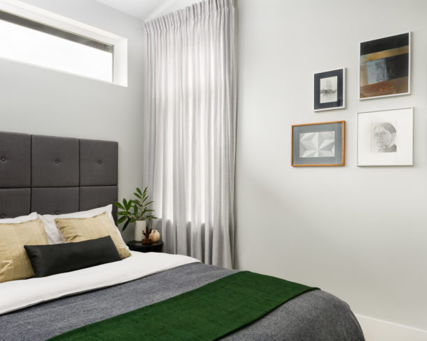 a basil green throw blanket placed on a grey bed