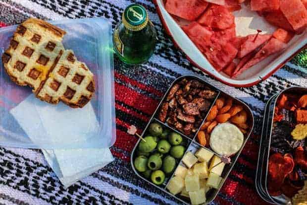 A waffled grilled cheese, a bento box filled with green olives, ,candied pecans, crackers, and Tillamook cheese cubes.