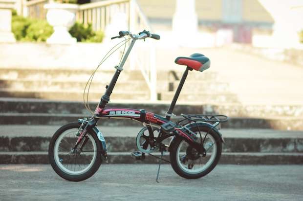 Folding bike parked with a kickstand in front of some steps