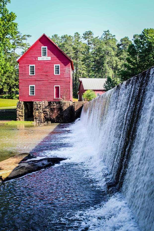 Starrs Mill red saw mill sits next to a water fall.