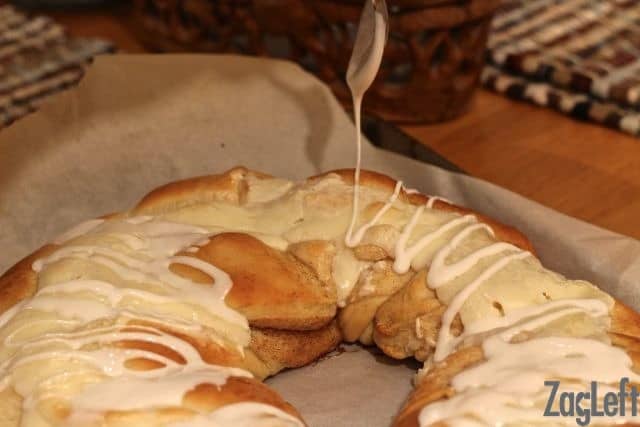 Drizzling white glaze over the top of the King Cake