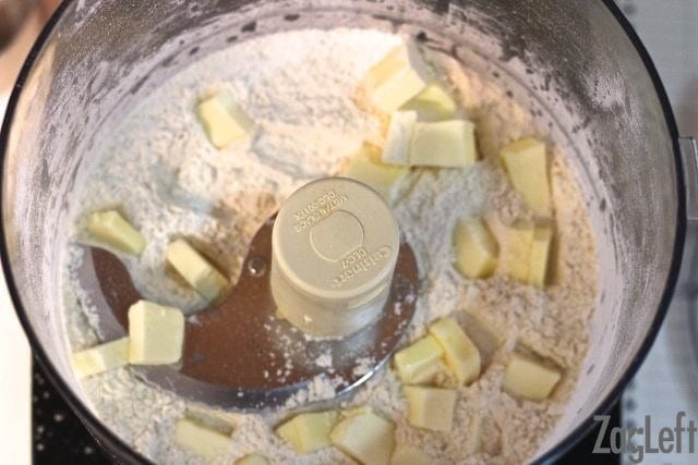 Adding butter slices to the dry ingredients in a food processor