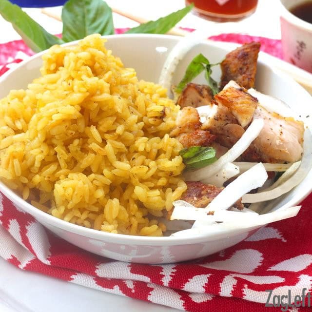 Bowl of chicken with golden rice and slices of onion